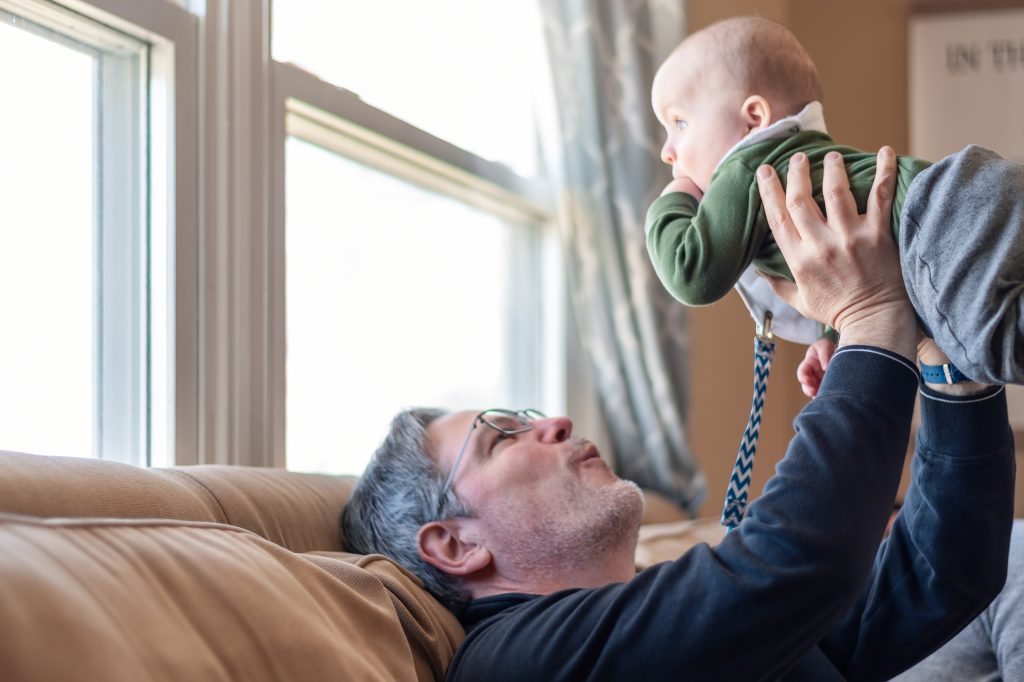 Grandpa lifting infant grandson in the air