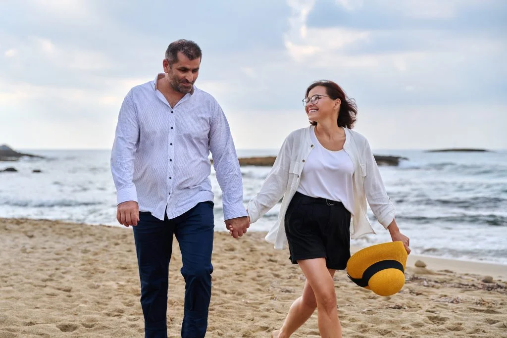 Happy middle-aged couple walking together on the beach